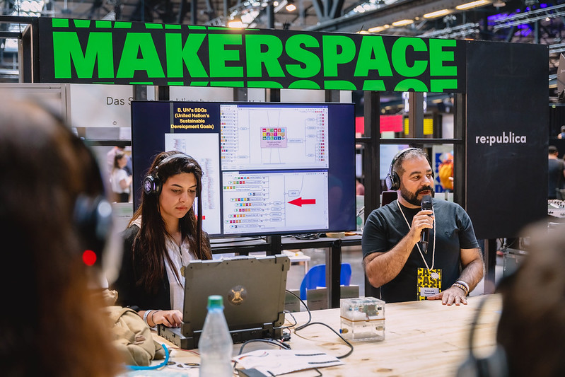 zwei Personen halten einen Workshop vor einem großen Schild "MAKERSPACE"
